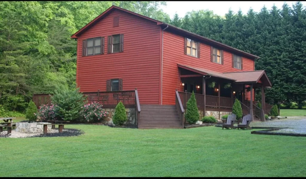 Red cabin with a spacious deck surrounded by lush greenery.