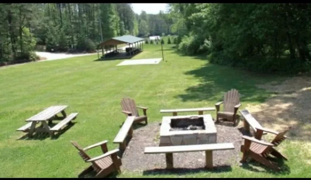 Outdoor fire pit with Adirondack chairs and picnic tables.